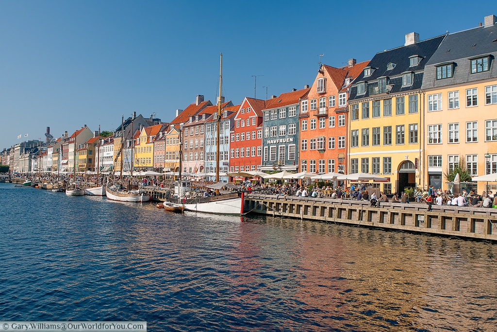 The view of the many bars that line Nyhavn, bathed in beautiful, summer, sunshine, Copenhagen, Denmark