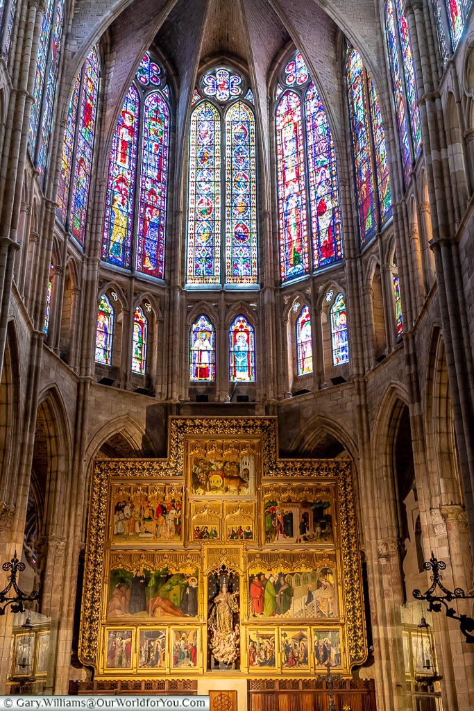 Stained glass windows above the painted wooden panels in the apse of Leon Cathedral