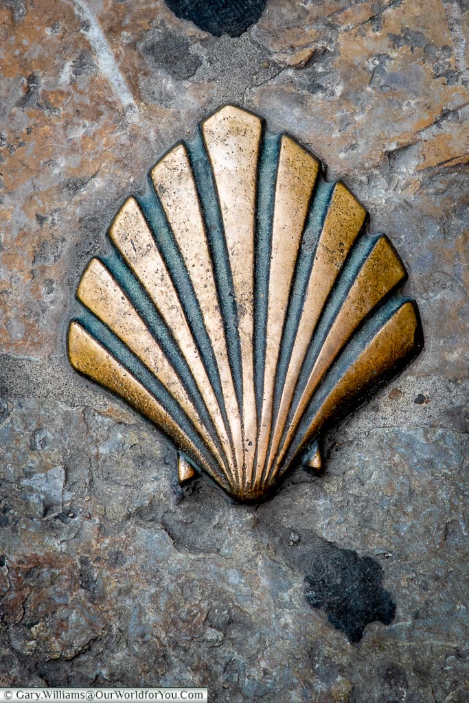 A close-up of a brass clamshell, set in the street in León, Spain.