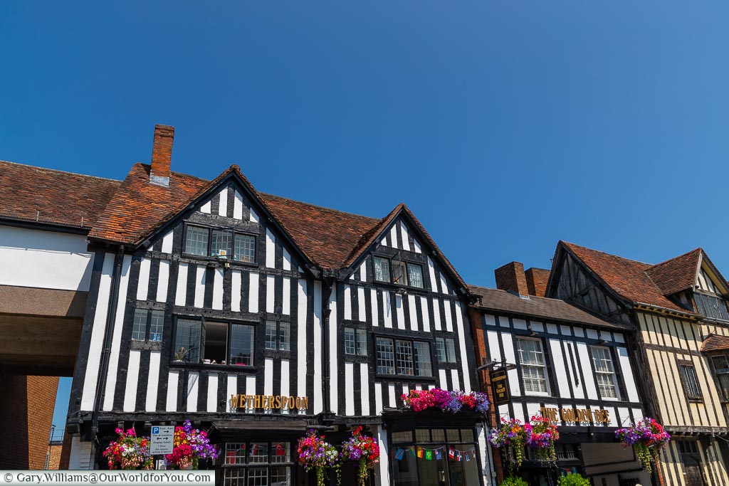 The Golden Bee pub, decorated with hanging baskets, in a timber-framed building on Sheep Street in Stratford-upon-Avon