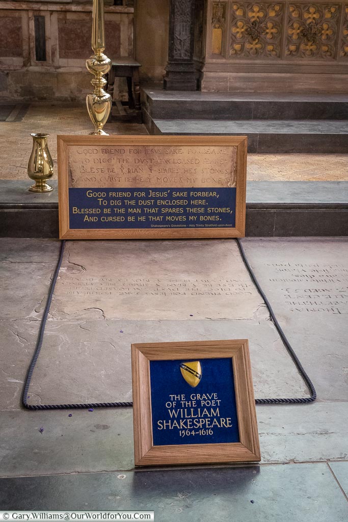A blue framed plaque in front of the grave of William Shakespeare inside the Holy Trinity Church in Stratford-upon-Avon