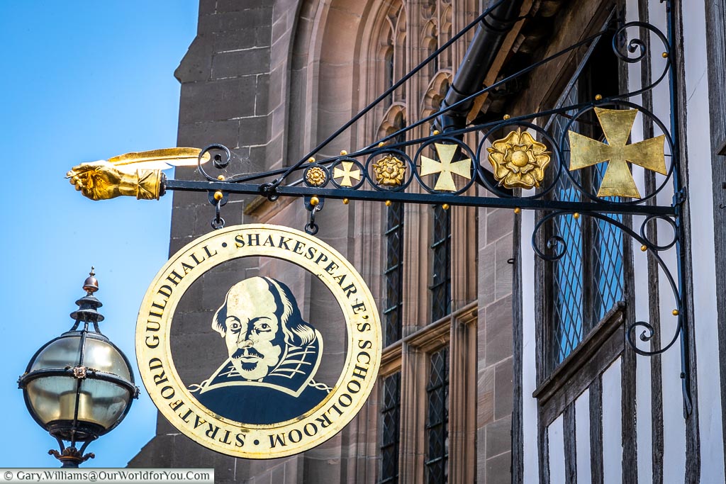 The wrought-iron and gold-trimmed sign attached to Shakespeare's Schoolroom & Guildhall on Henley Street in Stratford-upon-Avon