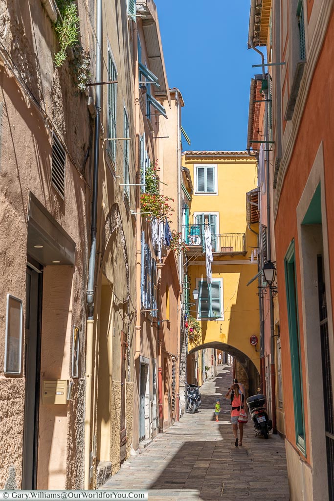 A narrow lane between bright coloured tall buildings in Villefranche-sur-Mer.
