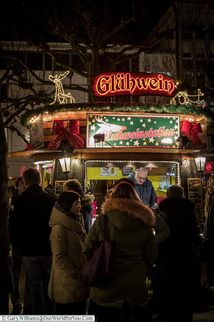 A group of people queuing at a Glühwein hut at the Hauptwach Christmas Market.