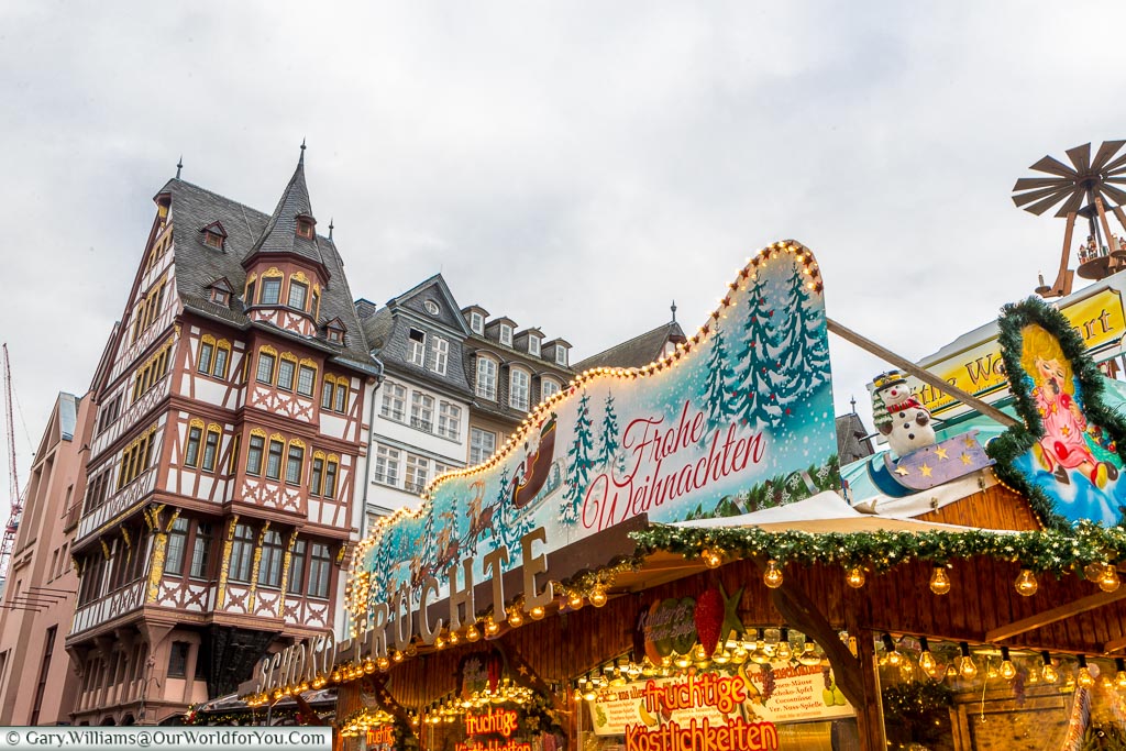 The ornate roof of a Christmas market stall in Römerberg in front of a half-timber building.