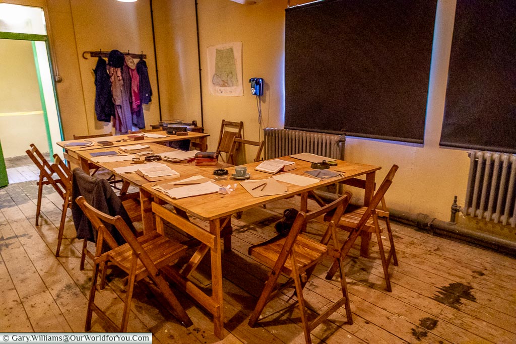 A mocked-up meeting table of foldout wooden tables and chairs in a stark room in hut 6 in Bletchley Park