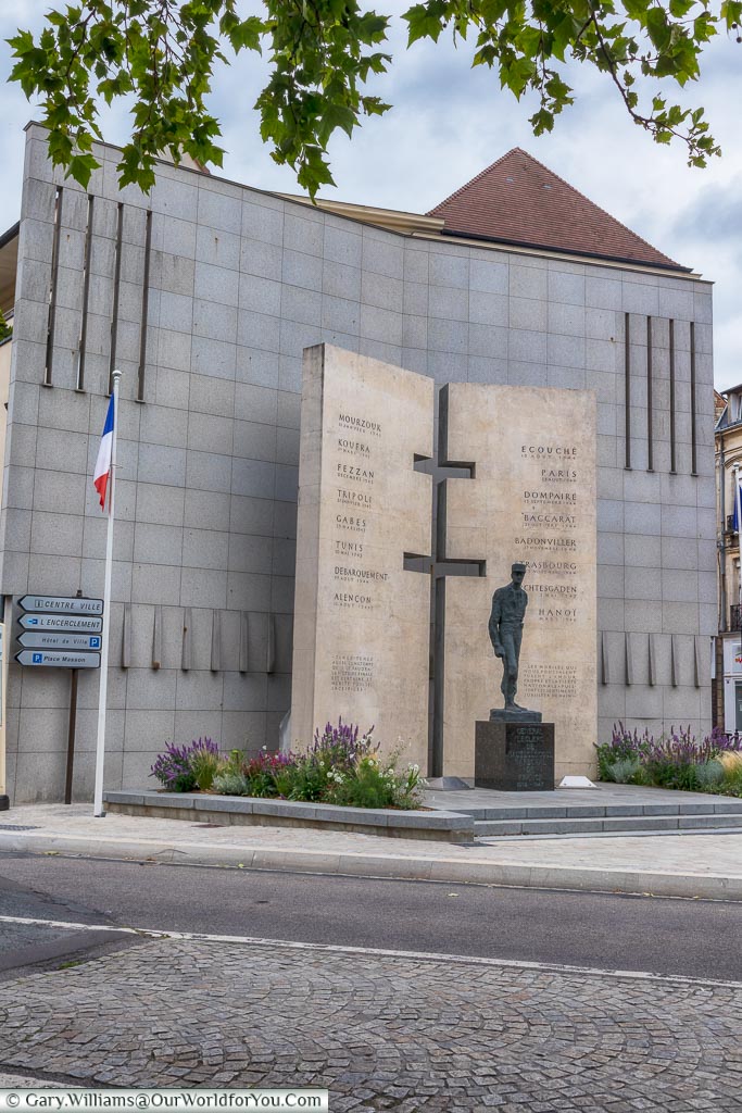 The memorial to General Leclerc in Alençon.  The brass statue of Leclerc stands in front of two large tables that list his campaigns, with a Cross of Lorraine extruded from join in them.