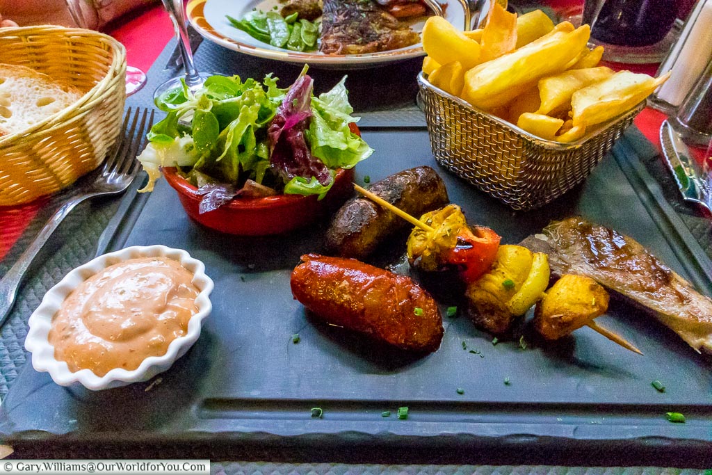 A meat feast served with a salad and chunky fries.