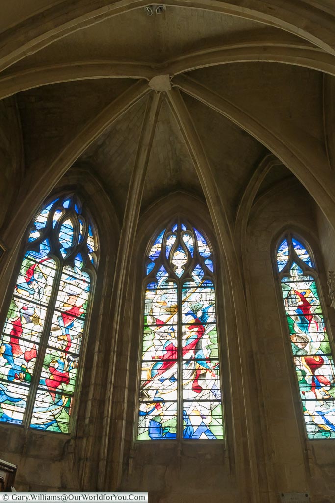 A modern art stained glass window under the vaulted ceiling of a chapel within the Basilica of Notre-Dame in Alençon, Normandy.