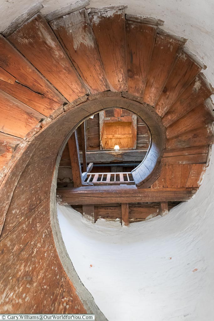 Looking up the wooden spiral staircase, built between white plastered walls, in Upnor Castle