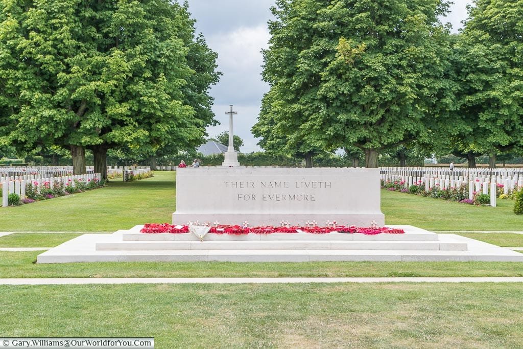 The 'Stone of Remembrance', with the 'Cross of Sacrifice' in the background, flanked on each side by headstones, at the Bayeux Commonwealth Military Cemetery in Normandy.