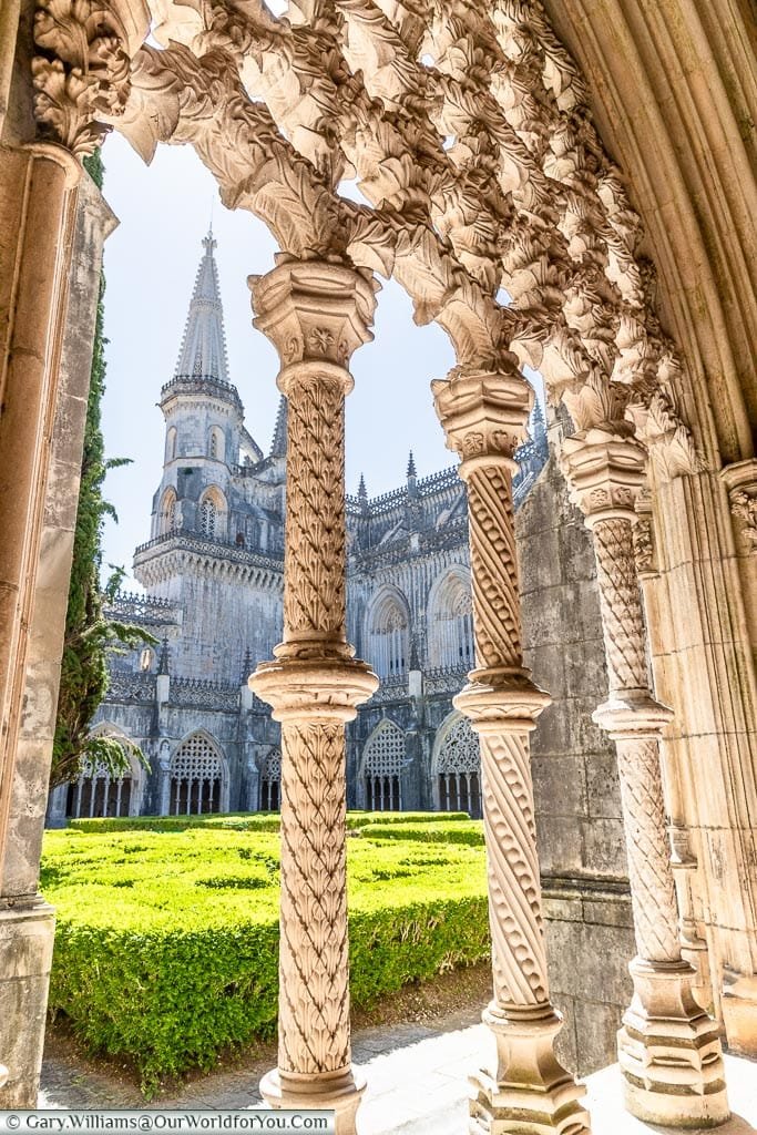 Looking through the decorative arched stonework of the Royal Cloisters in the Monastery of Batalha to the tower beyond which we visited on our road trip in portugal.