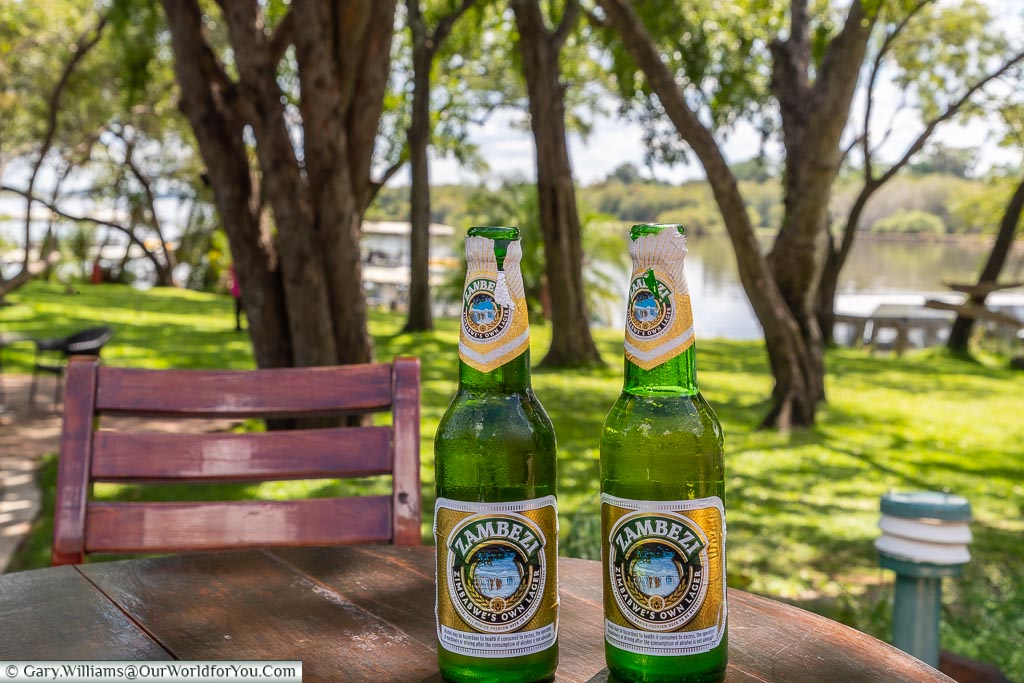 Two bottles of Zamedia beer on our table at the edge of the Zambezi River at Victoria Falls in Zimbabwe