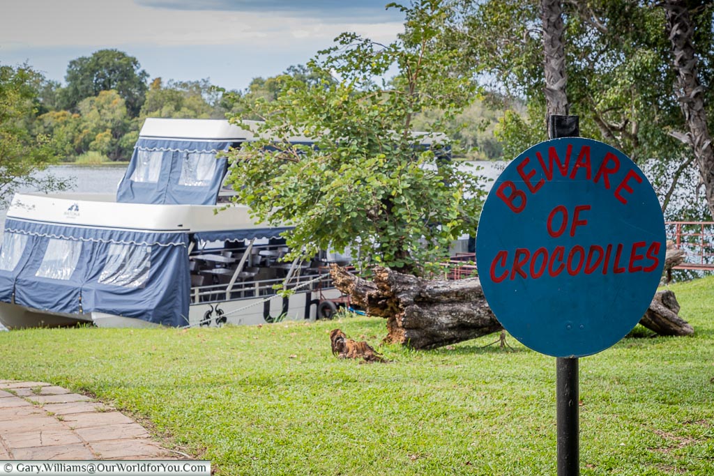 A blue sign warning "Beware of Crocodiles", in the grounds of the A’Zambezi River Lodge at Victoria Falls, Zimbabwe