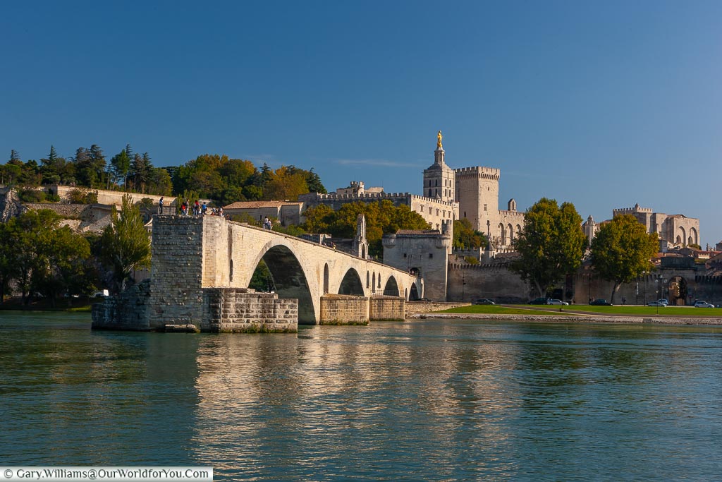 The view of Pont d’Avignon, from across the river Rhône, with the Palais des Papes in the background
