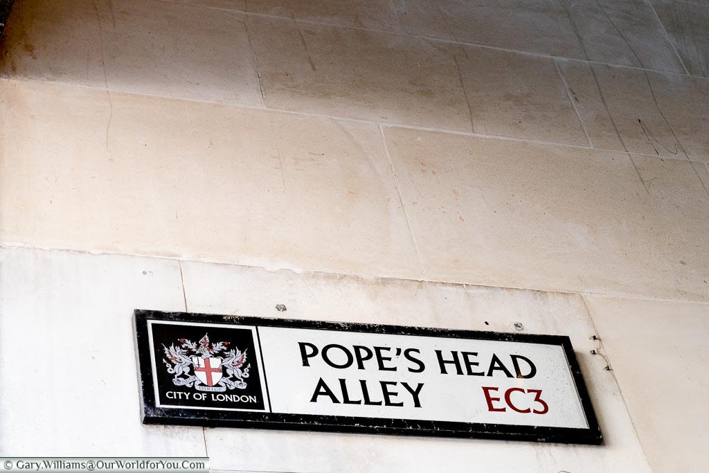 A City of London street sign for Pope's Head Alley mounted on a stone wall in the EC3 district of London