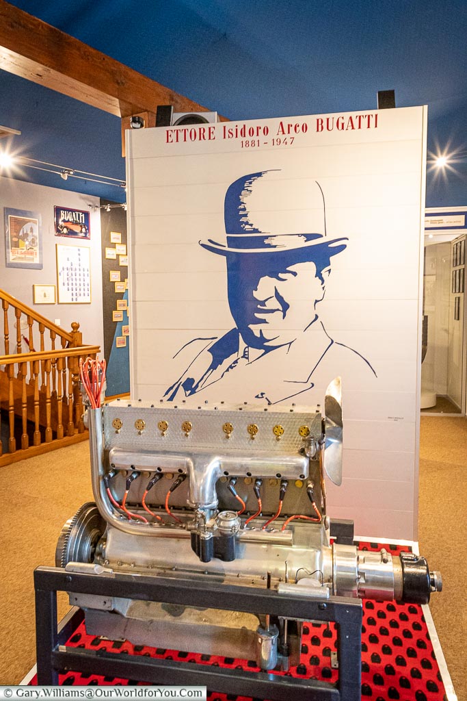 A display inside the Bugatti museum of a type 45 engine infron of an image of Ettore Bugatti.