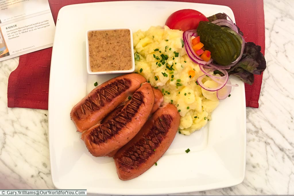 A plate of grilled Regensburger sausages served with potato salad pickles, and mustard from the Ratskeller, Regensburg.