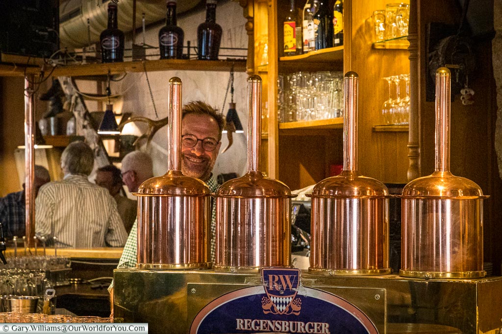 The view of the bar inside the Regensburger Weissbräuhaus, Regensburg, dominated by polished copper pumps and a friendly, smiling, barman.