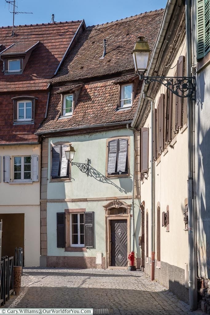 A cobbled lane in Molsheim, each house a different colour with red tiled roofs.