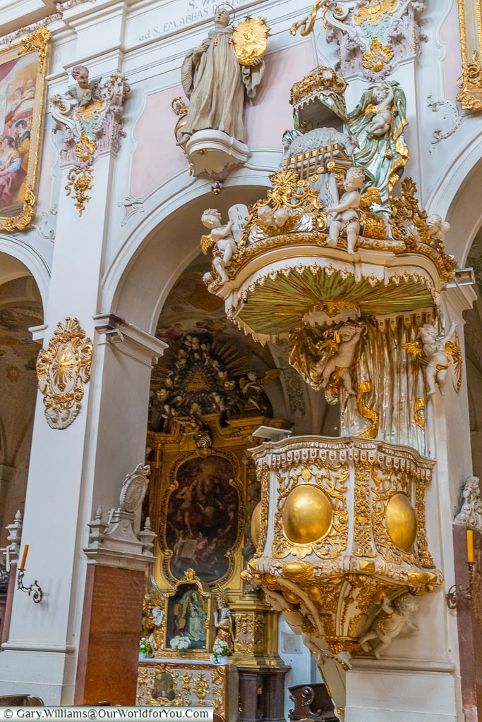 The ornate pulpit in St. Emmeram's Abbey, decorated in gold leaf in a Rococo style.