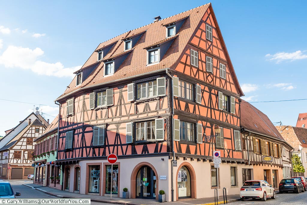 A half-timber building, typical of Alsatian architecture painted in a dusky orange colour.