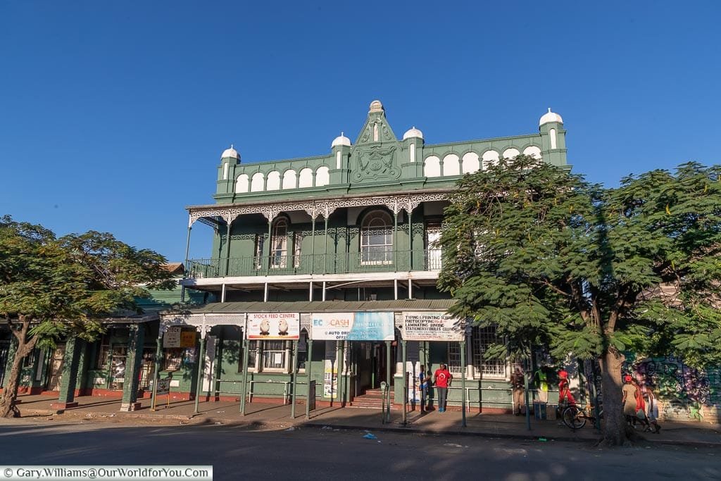 A green & white colonial building against a deep blue sky.