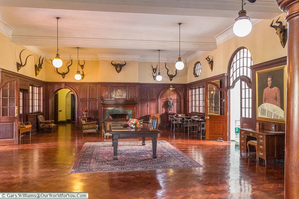 The wooden panelled reception area of the Bulawayo club in a colonial style with mounted antelope heads adorning the upper part of the walls.