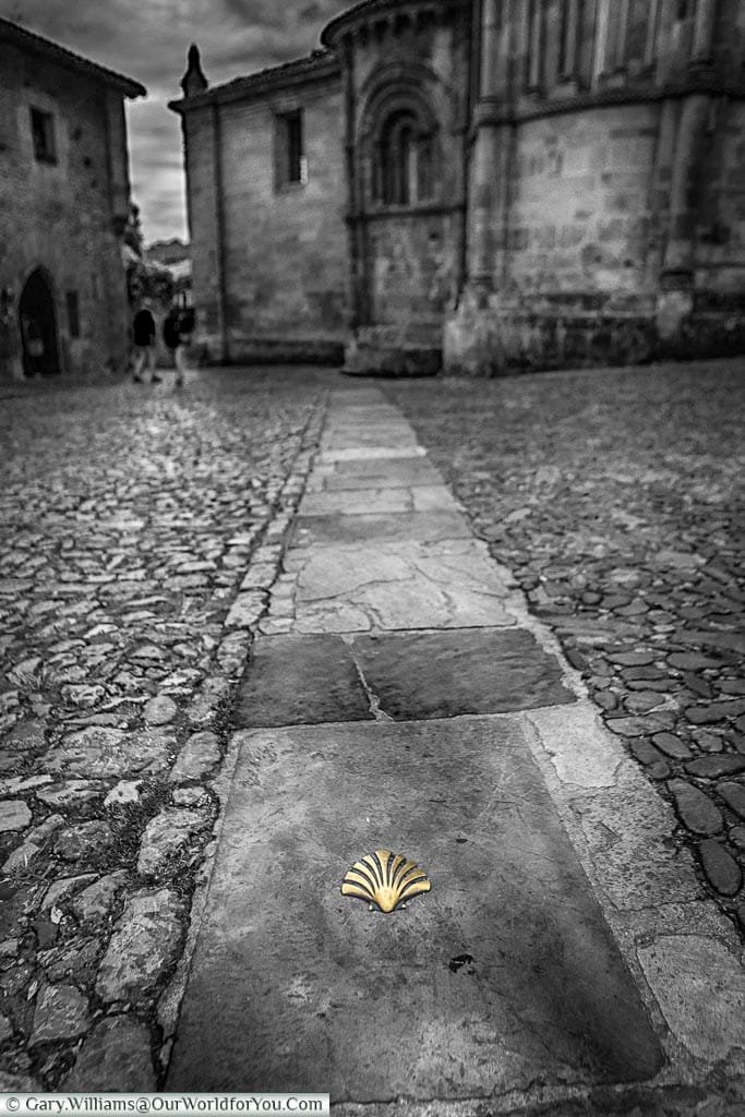 A black and while image with a coloured brass clam plaque on the path.
