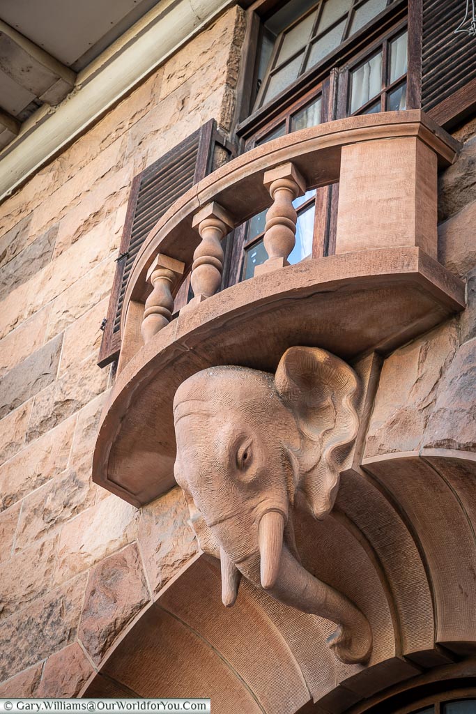 An elephant head detail carved out of stone under a balcony.
