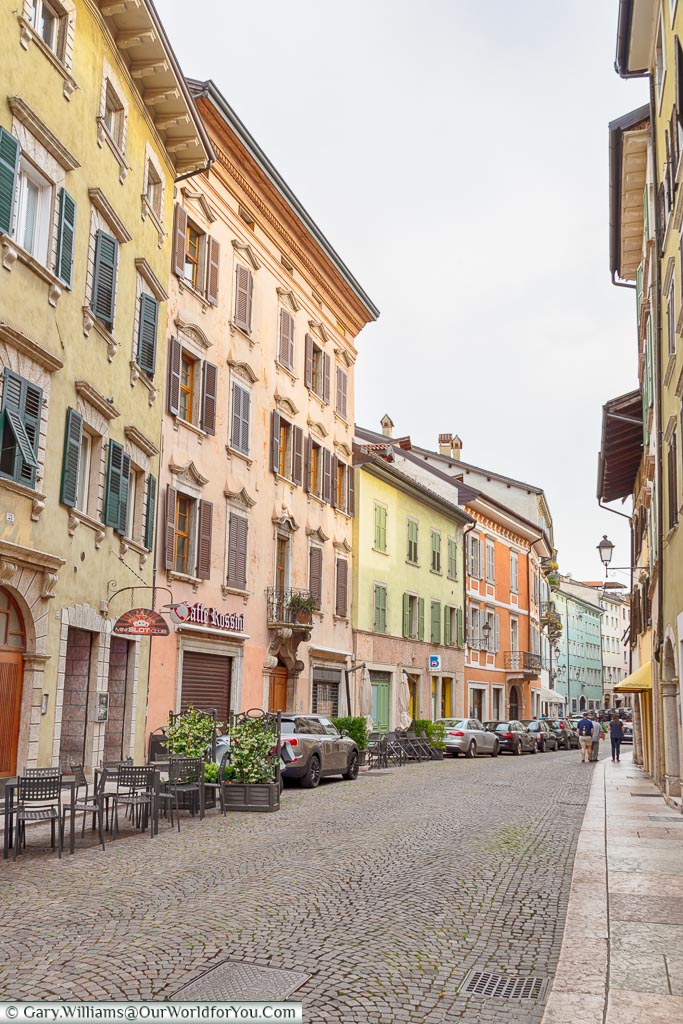 A street scene of Trento with pastel coloured four-storey buildings.