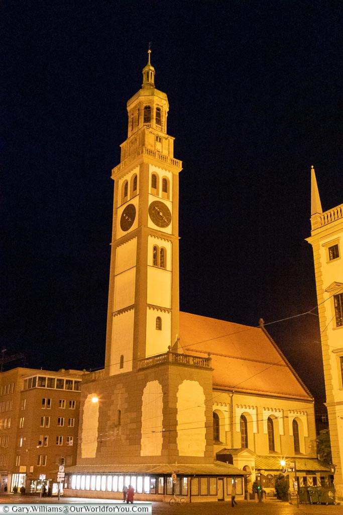 A tall bell tower, illuminated against the night sky, known as the Perlachturm.
