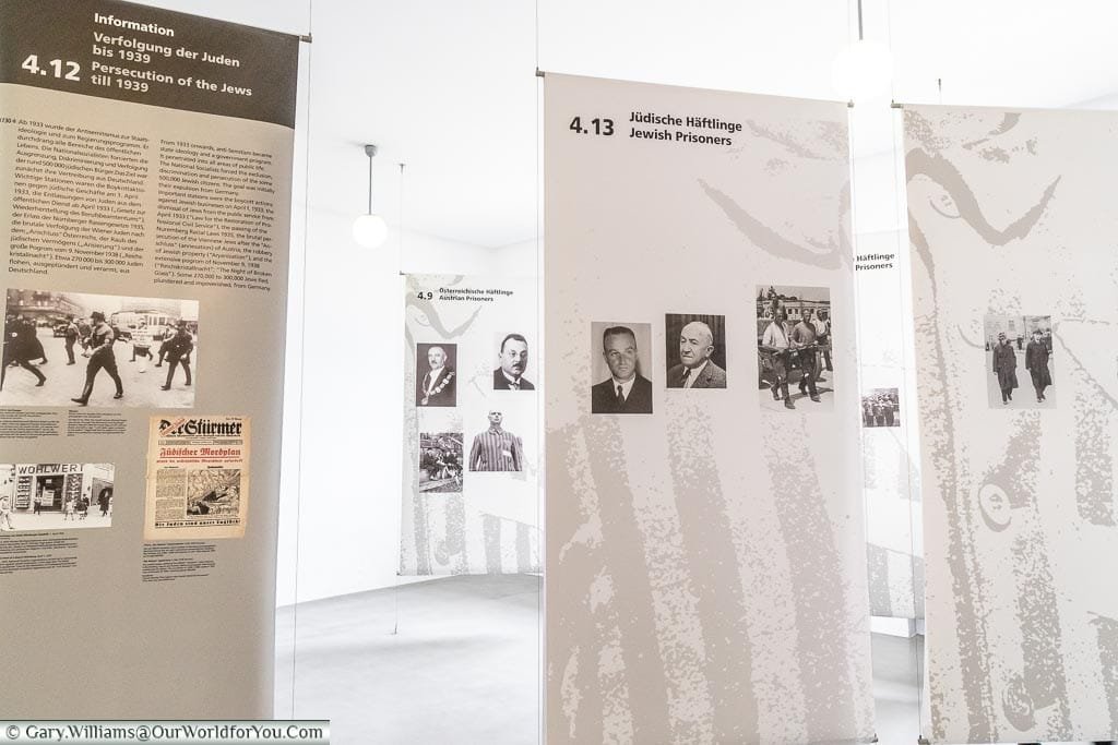 Inside a corner of a museum where drapes display information of the horrors of the camps with supporting images.