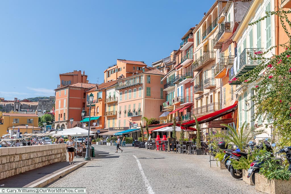 A street view of the quayside at Villefranche-sur-Mer with its pastel-coloured buildings and quaint cafés.