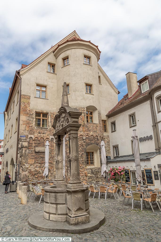 An old stone well in front of a historic building.