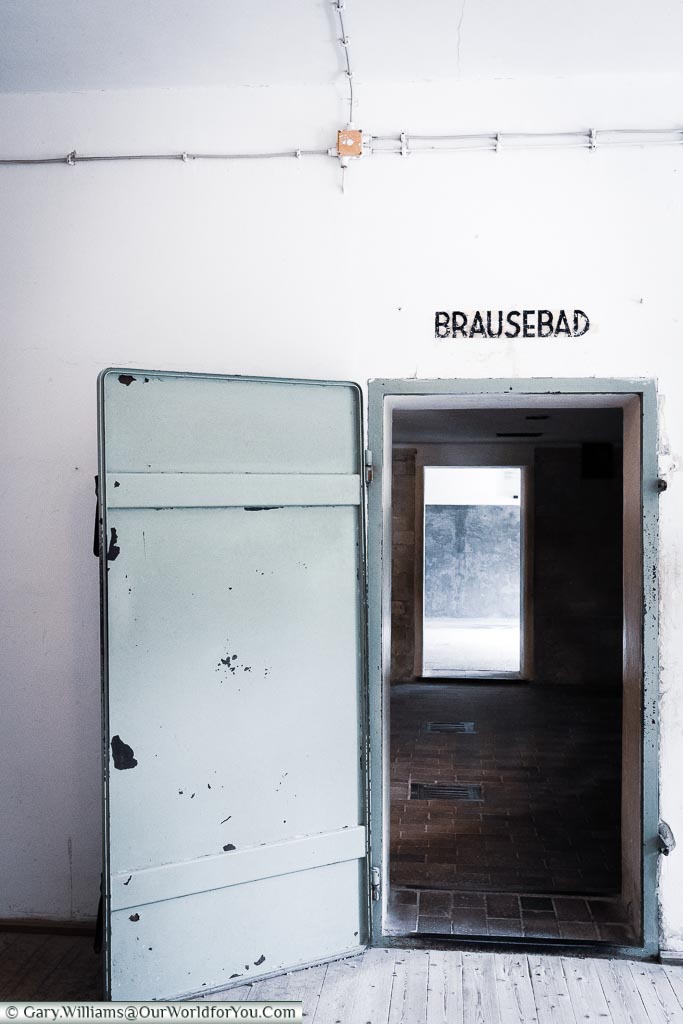 An iron door that led to the gas chamber the camp. Above the door is a sign for Brausebad - Shower/Bath.