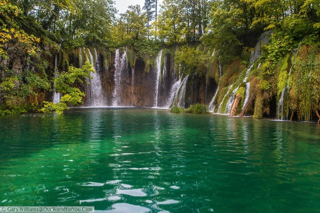 At water level overlooking a sizeable opal-coloured pool being fed by waterfalls on all sides.