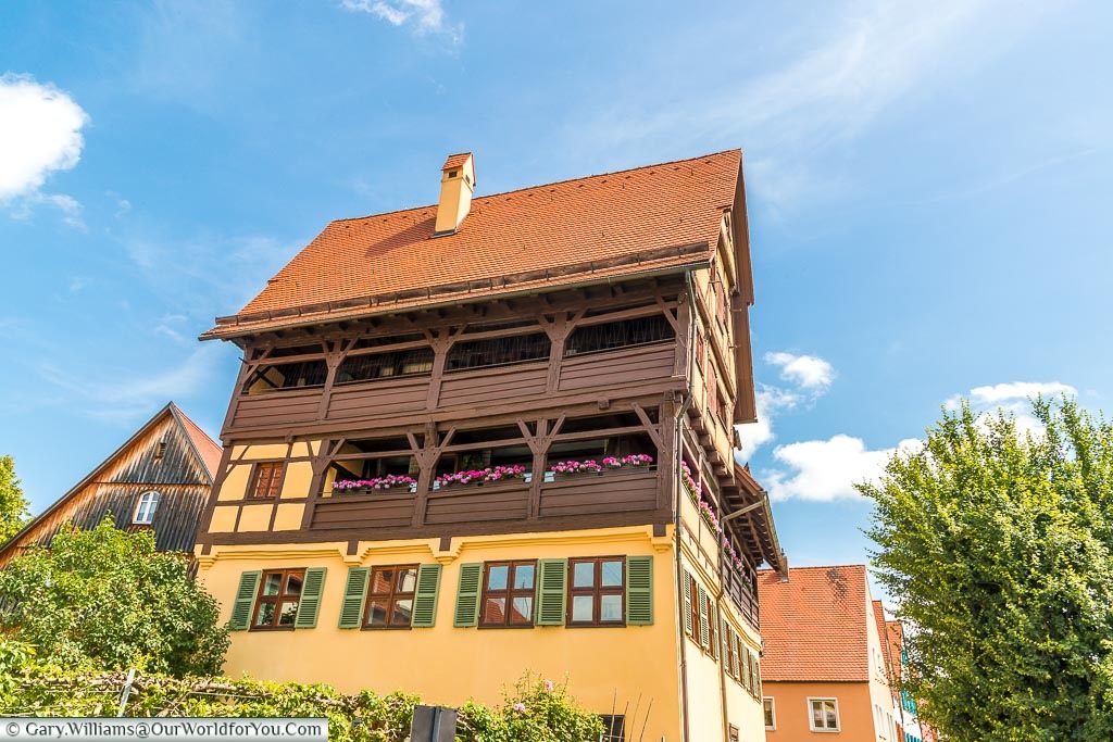 A traditional home with gabled upper decks with brightly coloured flower boxes on the middle row.