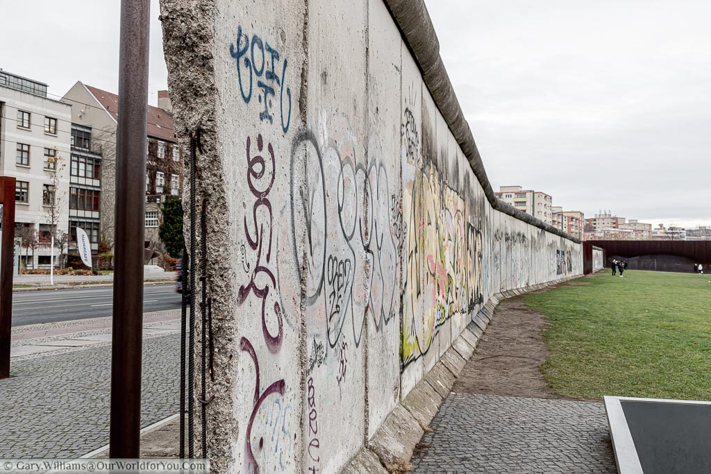 A view of a split in the Berlin Wall allowing you to see both the east & west sides.