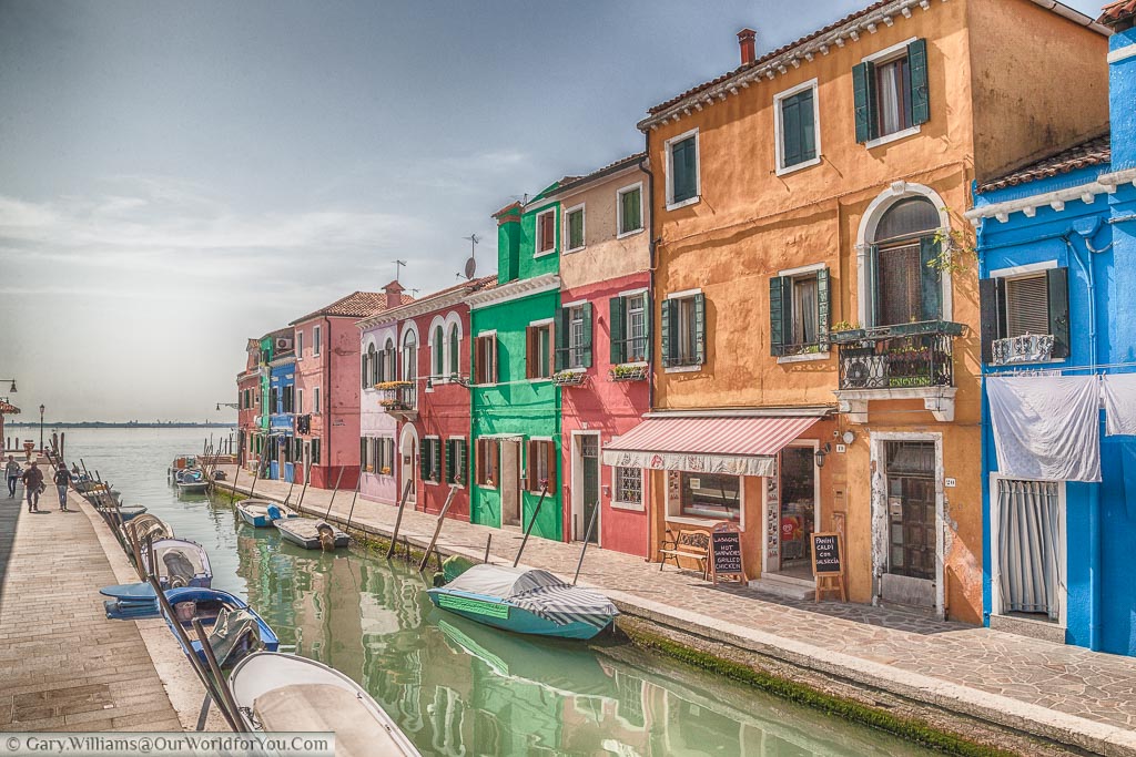 The pretty painted houses either side of a canal in of Burano leading out to the lagoon separates it from Venice