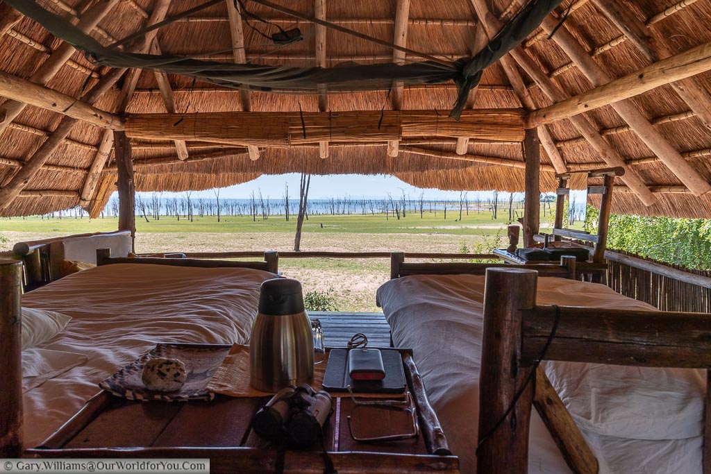 The windlowess interior of the lodge under a thatched roof with a view over Lake Kariba