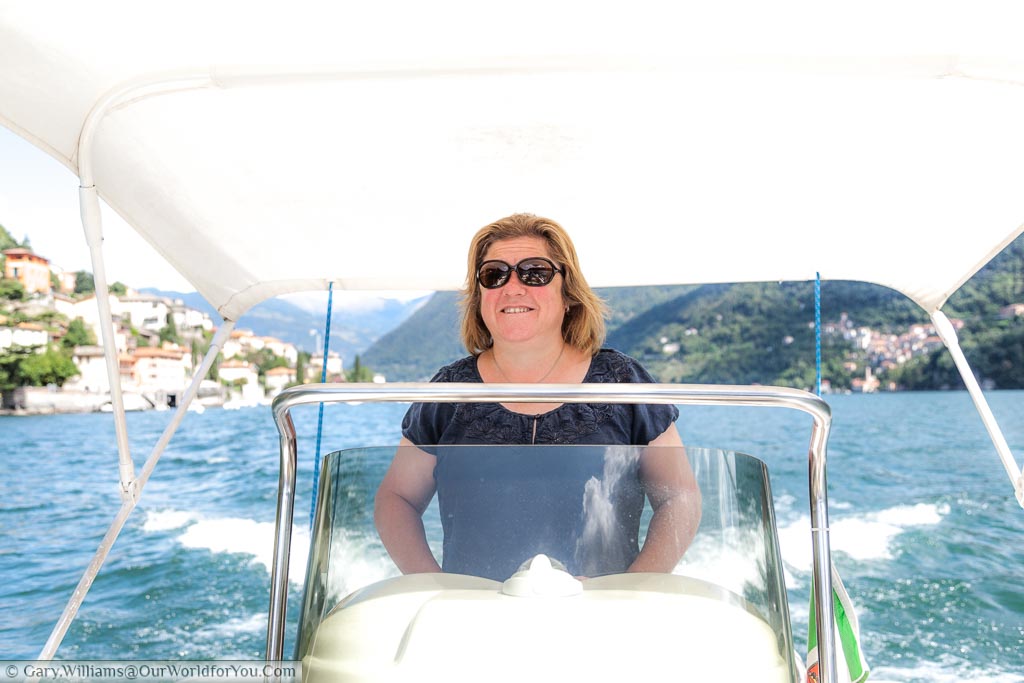 Janis at the controls of our hired speed boat on Lake Como, underneath the white shade canopy that provides protection against the sun.
