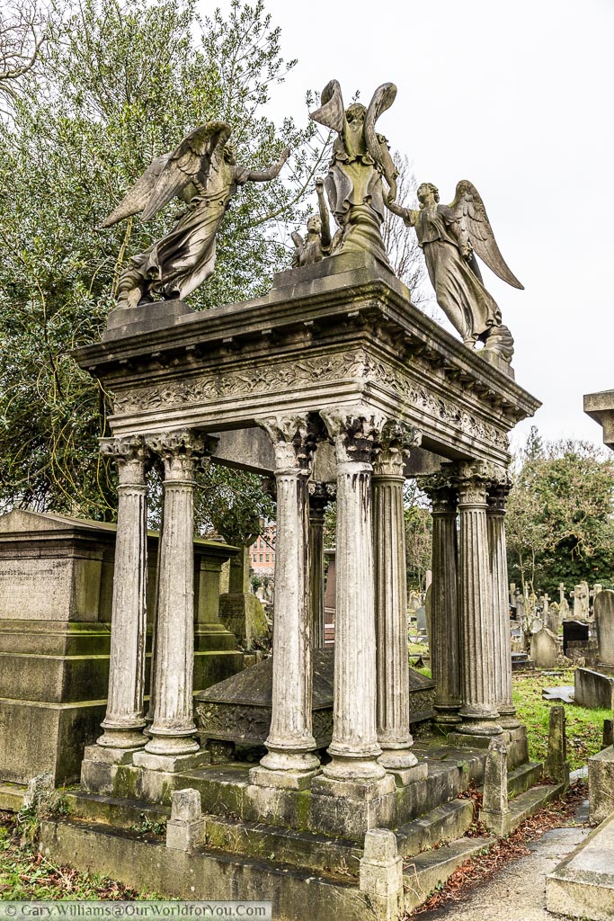 Another tomb at the Kensal Green Cemetery, surrounded by columns with a canopy and four angels on the roof.