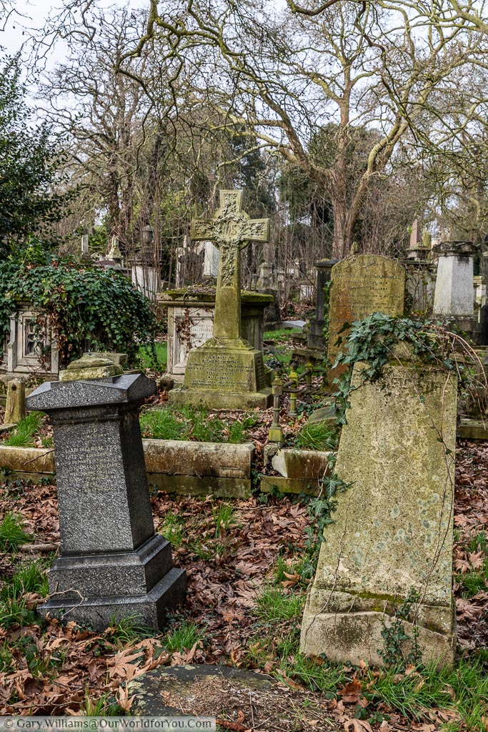 A selection of old gravestones at Kensal Green Cemetery that are all leaning at different angles.