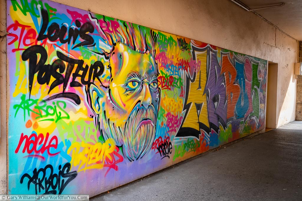 A bright mural celebrating a hero of Arbious, the French scientist Louis Pasteur, on a wall next tot he towns public library.