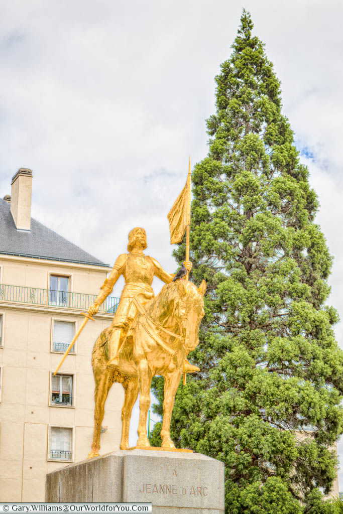 A golden equine statue to Joan of Arc carrying a flag in Caen, Normany