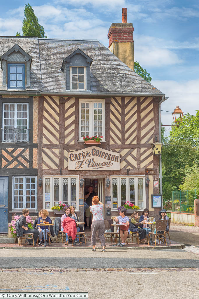 The people sitting outside the pretty little Café du Coiffeur F. Vincent in Beuvron-en-Auge