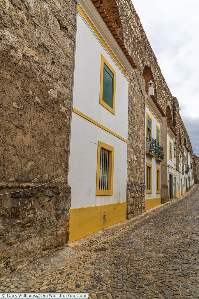 Homes in Évora, built between the arches of the aqueduct, each one in the traditional white and yellow of the region.
