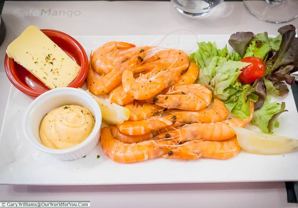 A plate of bright orangy-pink prawns with a light side salad and a mayonaise dip in Cafe Magon in Caen, Normandy