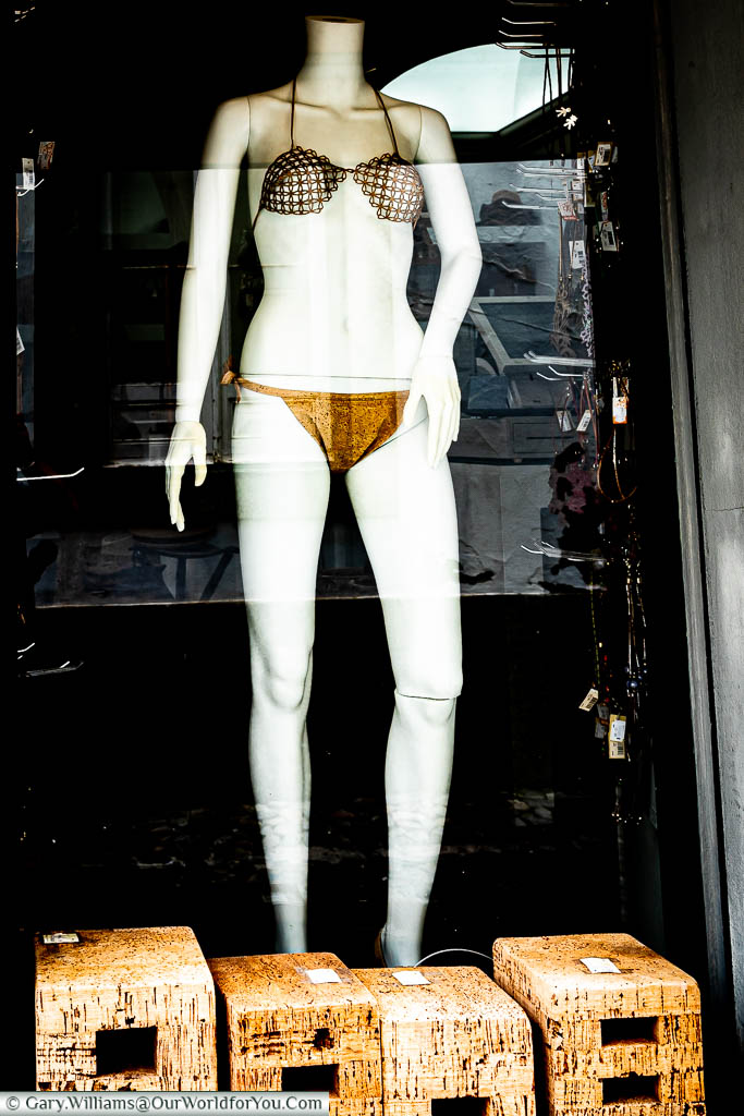 A mannequin, wearing a cork bikini, in a window display, that is going to show way too much.